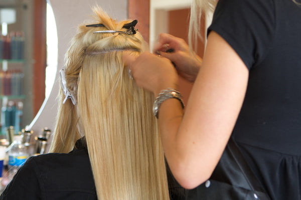 Hair extensions care, hair extensions technician working on a client